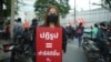 Baifern Benjama, a pro-democracy protester, holds a sign reading "Reform = make it better," at a Bangkok street protest. (Vijitra Duangdee/VOA)