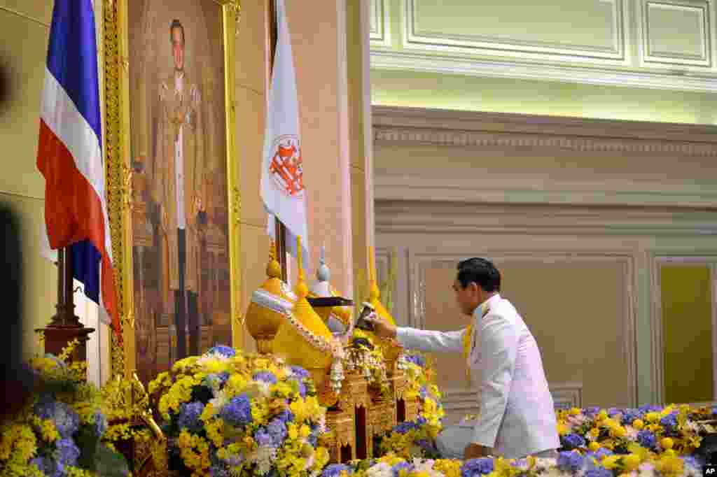 Gen. Prayuth Chan-ocha opens a container before he accepts a royal endorsement certifying his appointment as the country's 29th premier, in front of the portrait of King Bhumibol Adulyadej in Bangkok, Aug. 25, 2014.