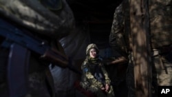 Un soldado ucraniano habla con sus camaradas sentados en un refugio en la línea de separación entre el territorio controlado por Ucrania y el territorio controlado por los rebeldes cerca de Svitlodarsk, en el este de Ucrania, el miércoles 23 de febrero de 2022.