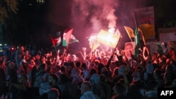Protesters lift Palestinian flags and a portrait of Mohammed Deif chief of Al-Qassam Brigades, Hamas' military wing, during a rally at the entrance of the French embassy complex in Beirut early on Oct. 18, 2023.