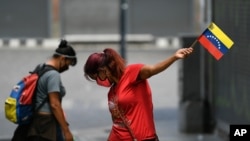 Una mujer con un tapabocas sostiene una bandera venezolana durante el Día de la Independencia en Caracas, el 5 de julio de 2020..