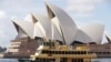 Sebuah kapal feri berlayar melewati Opera House di Sydney, Australia, Selasa, 6 April 2021. Australia yang kaya batu bara mengungkapkan target nol emisi bersih pada 2050. (Foto: AP)