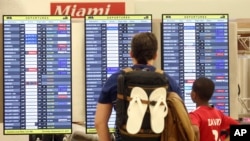 Passengers check the departure board at Miami International Airport, Sept. 7, 2017. 