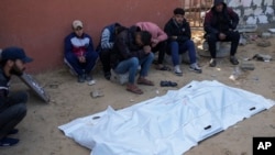 Familiares de un palestino muerto en los ataques nocturnos de Israel lloran junto a su cuerpo, fuera de la morgue del hospital Nasser en el campo de refugiados de Jan Yunis, en el sur de la Franja de Gaza, el sábado 4 de enero de 2025. (AP Foto/Abdel Kareem Hana).