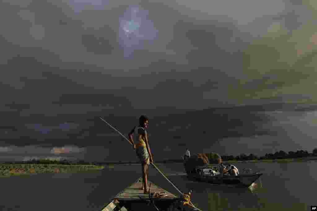 A boat carries flood relief materials as monsoon clouds surrounded the flood affected Gagalmari village in Assam state, India, July 2, 2012.