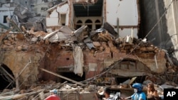 Libaneses pasan por delante de una de las casas destruidas por la explosión ocurrida el martes 4 de agosto de 2020 que mató a más de un centenar de personas, hirió a unas 5.00. y más de 300.000 quedaron sin hogar.