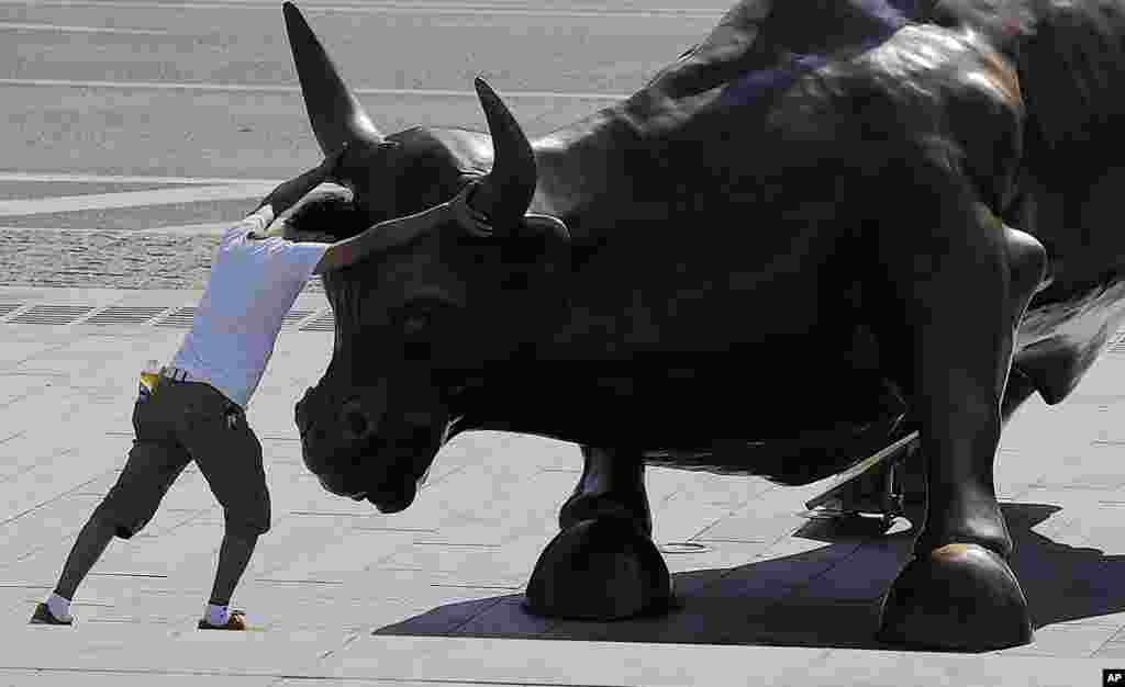 Seorang pengunjung berpura-pura berkelahi dengan patung banteng "Charging Bull" yang dibuat oleh seniman Italia Amerika Arturo Di Modica di Shanghai, China.