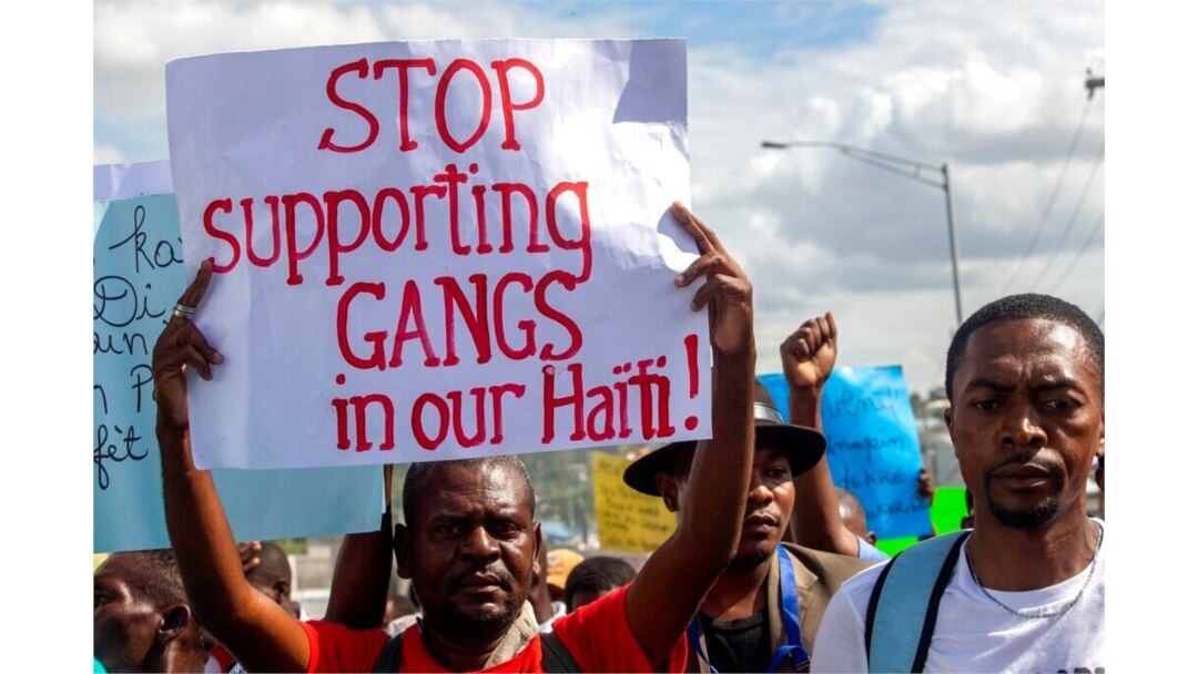 FILE - A protester holds a sign with a message to stop supporting gangs during a protest in Port-au-Prince, Haiti, Dec. 10, 2020.