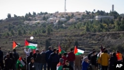 FILE - Palestinians protest against expected visit of the U.S. Secretary of State Mike Pompeo to the Jewish settlement of Psagot near the West Bank city of Al-Bireh, Nov. 18, 2020.
