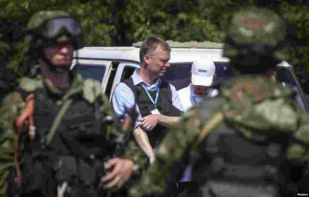 Alexander Hug (center), deputy head of OSCE, Europe's monitoring mission in Ukraine, stands next to armed pro-Russian separatists as the convoy makes its way to the MH17 crash site outside Donetsk, July 30, 2014.