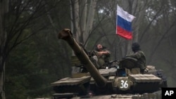 Pemberontak pro Rusia mengendarai tank berbendera Rusia di wilayah Donetsk (21/7). Pentagon mengatakan memiliki informasi transfer persenjataan dari Rusia ke pemberontak Ukraina. 