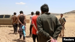 FILE - Men, believed to be Islamic State fighters, are taken prisoner after Democratic Forces of Syria fighters advanced in the southern rural area of Manbij, in Aleppo Governorate, Syria, May 31, 2016. 