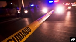 FILE - Police tape that reads in Spanish "Caution" marks off a crime scene in Tijuana, Mexico.