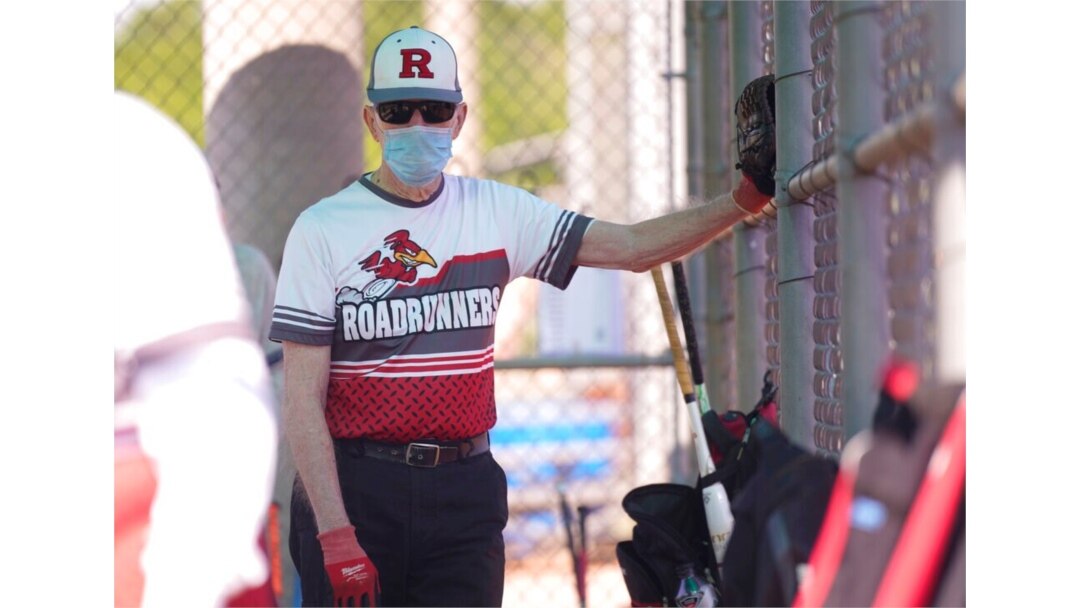 FILE - John Journey, 86, wearing a mask to the prevent the spread of COVID-19, listens to his team coach speak in the dugout before a 65-and-over league softball game, April 20, 2021, in Richardson, Texas.