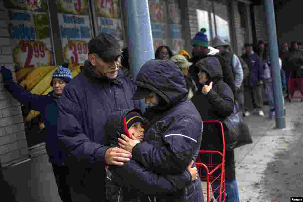 Julio dan Belinda Ramos, yang mengalami pemadaman listrik, bersama putra mereka Charles, 8, saat mengantri membeli persediaan makanan di supermarket di New York (30/10).