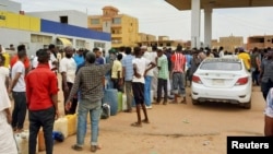La gente se reúne para conseguir combustible en una estación, mientras continúan los enfrentamientos entre las Fuerzas de Apoyo Rápido paramilitares y el ejército, en el sur de Jartum, Sudán.