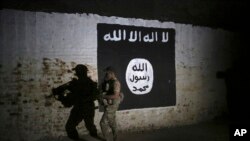 FILE - An Iraqi soldier inspects a train tunnel, adorned with an Islamic State group flag, that was used as training camp for IS fighters, in western Mosul, Iraq, March 1, 2017.