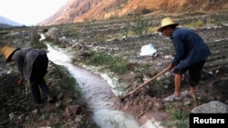 Para petani di distrik Dongchuan di Kunming, provinsi Yunan dekat aliran air sungai yang tercemar. (Foto: Dok)