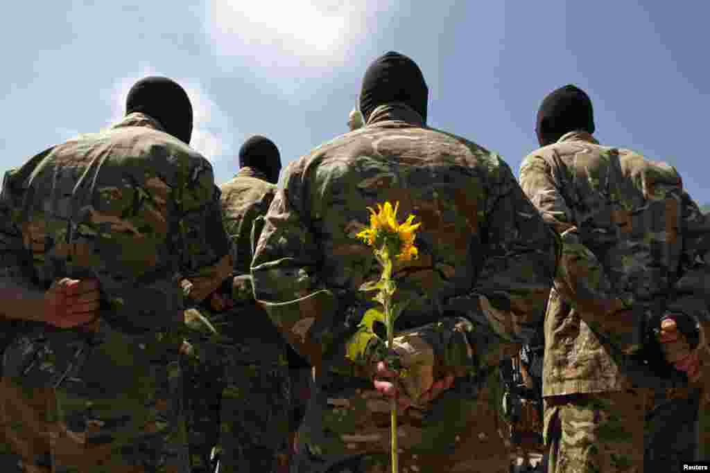 A new volunteer of the Ukrainian self-defense battalion "Azov" holds a sunflower during a ceremony. He will take an oath of allegiance to his country during the ceremony, in Kyiv, July 16, 2014.