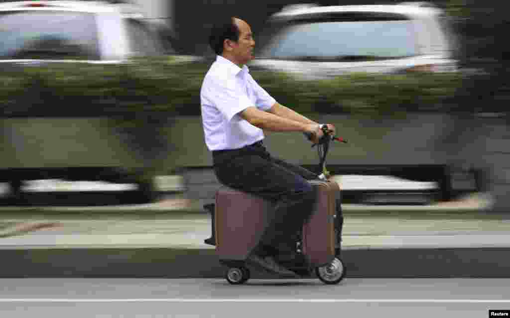 He Liang mengendarai "koper-motor" buatan sendiri di kota Changsha, Hunan, China.