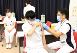 FILE - Medical workers receive doses of Pfizer's COVID-19 vaccine at the Tokyo Metropolitan Cancer and Infectious Diseases Center Komagome Hospital in Tokyo, March 5, 2021.