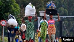 People displaced by fighting between Congolese forces and M23 rebels make their way home after spending a night in the Ugandan town of Bunagana, Oct. 31, 2013.