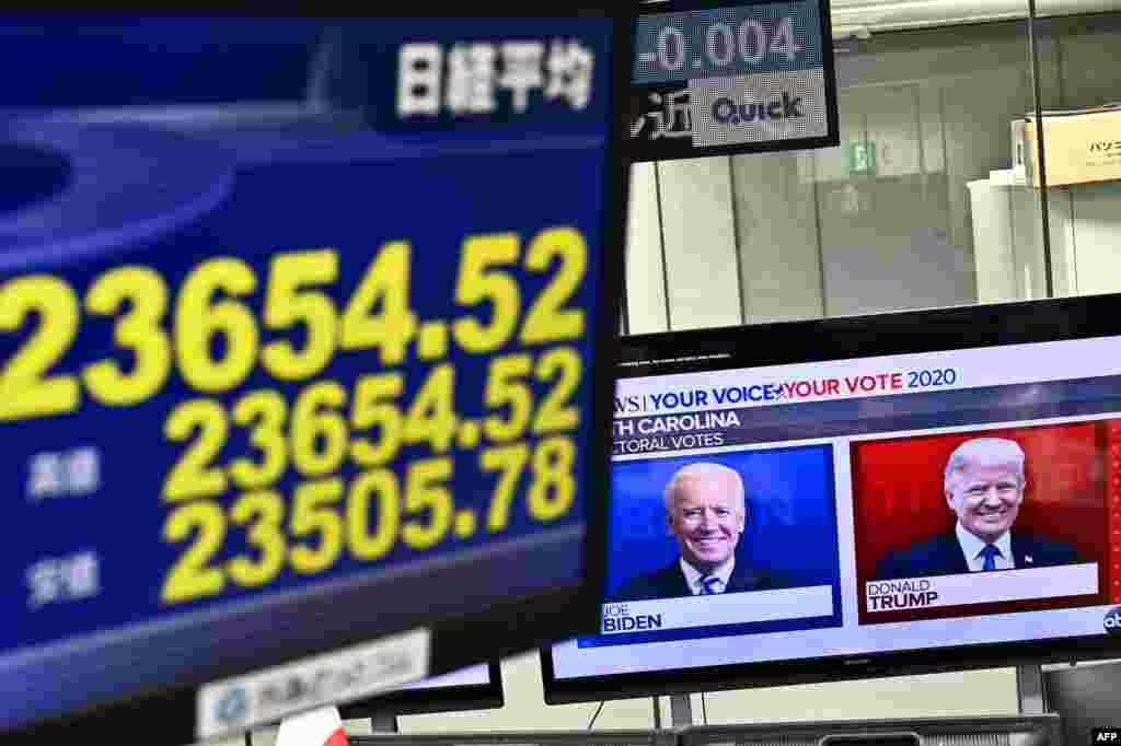 Una pantalla muestra los precios de las acciones de la Bolsa de Valores de Tokio como un canal de noticias que presenta retratos de los candidatos presidenciales de los EE.UU. Donald Trump y Joe Biden en una compañía de comercio de divisas en Tokio.