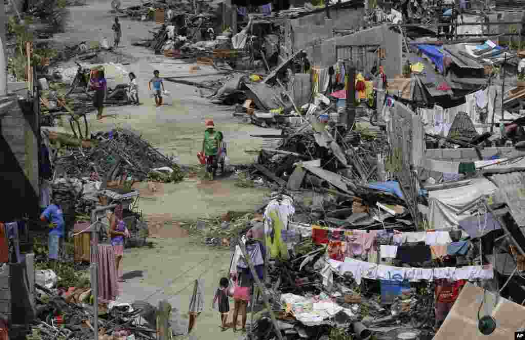 Survivors of Typhoon Haiyan walk amid ruins of their homes in Maraboth, Philippines, Nov. 14, 2013. 