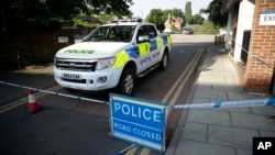 A British police vehicle stands parked next to an area which was extended overnight to include the Lush House car park adjacent to the Queen Elizabeth Gardens park in Salisbury, England, Thursday, July 5, 2018. The area has been linked to what is believed to be another chemical incident involving a nerve agent.