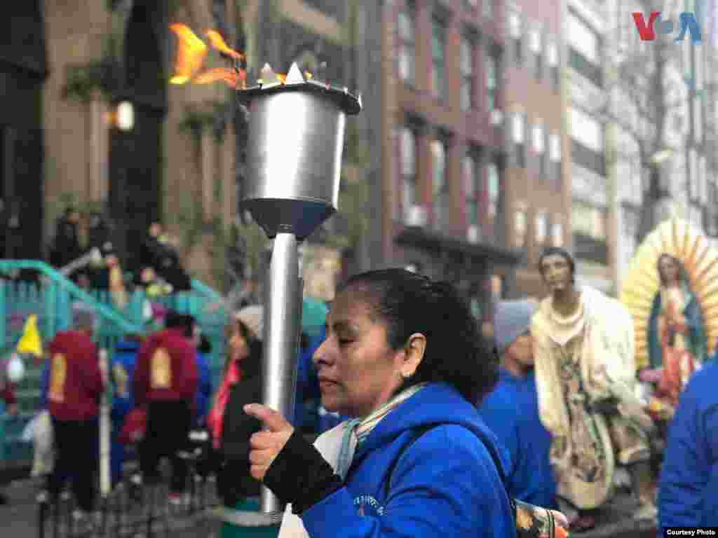Una señora sostiene una torcha mientras camina en las calles de la Ciudad de Nueva York, rumbo a la Catedral de San Patricio. Foto: Celia Mendoza- VOA