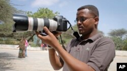 Wartawan Somalia Mohamed Mohamud memegang kameranya saat meliput di komplek Rumah Sakit Medina di Mogadishu, Somalia. Mohamud terbunuh saat melaksanakan tugas pada tahun 2013. (Foto:dok)
