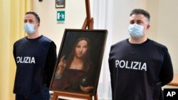 Policías italianos posa junto a una copia del "Salvator Mundi" (Salvador del mundo) de Leonardo da Vinci, en Nápoles, Italia, el miércoles 20 de enero de 2021.