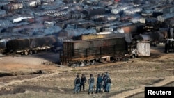 Afghan policemen stand at the site of burning fuel trucks after an overnight attack by the Taliban on the outskirts of Kabul, July 5, 2014.