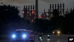 La gente conduce sus vehículos junto a un generador flotante en funcionamiento, en La Habana, Cuba, el martes 22 de octubre de 2024.