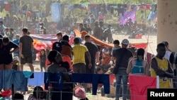 Migrants stand near the International Bridge between Mexico and the U.S., in Del Rio, Texas, Sept. 16, 2021, in this picture obtained from social media.