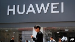 People walk past a Huawei retail store in Beijing, Sunday, June 30, 2019. (AP Photo)