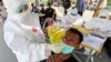 Seorang pekerja medis mengambil sampel usap hidung dari seorang pria selama tes virus corona wajib bagi mereka yang bepergian antara Pulau Madura dan Surabaya. (Foto: AP)