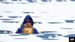 Un aficionado de los Buffalo Bills se sienta entre asientos llenos de nieve al inicio de un juego de la NFL entre los Buffalo Bills y los Steelers de Pittsburgh, el lunes 15 de enero, en Buffalo, Nueva York.
