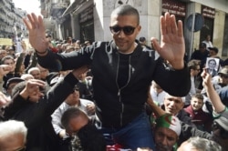 FILE - Algerian journalist Khaled Drareni is carried by protesters on their shoulders after he was briefly detained by security forces in Algiers, March 6, 2020.