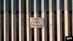 Un letrero en la frontera entre Estados Unidos y México dice en español "Todos somos migrantes" en Playas de Tijuana, noroeste de México, 18 de noviembre de 2018.