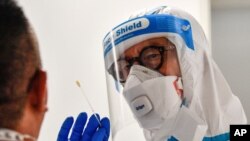 Un médico toma una prueba COVID-19 de un pasajero que llegó al aeropuerto de Duesseldorf, Alemania, el lunes 27 de julio de 2020.