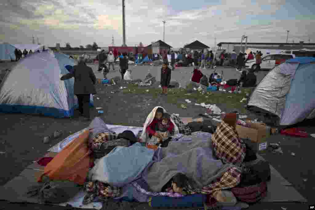 Afghan refugees are wrapped themselves with blankets to shelter from the morning cold after spending the night at a collection point in the truck parking lot of the former border station on the Austrian side of the Hungarian-Austrian border near Nickelsdo. European Union ministers agreed to relocate 120,000 migrants in a move intended to ease the strain on Greece and Italy which are on the frontline of the continent’s overwhelming migrant crisis.