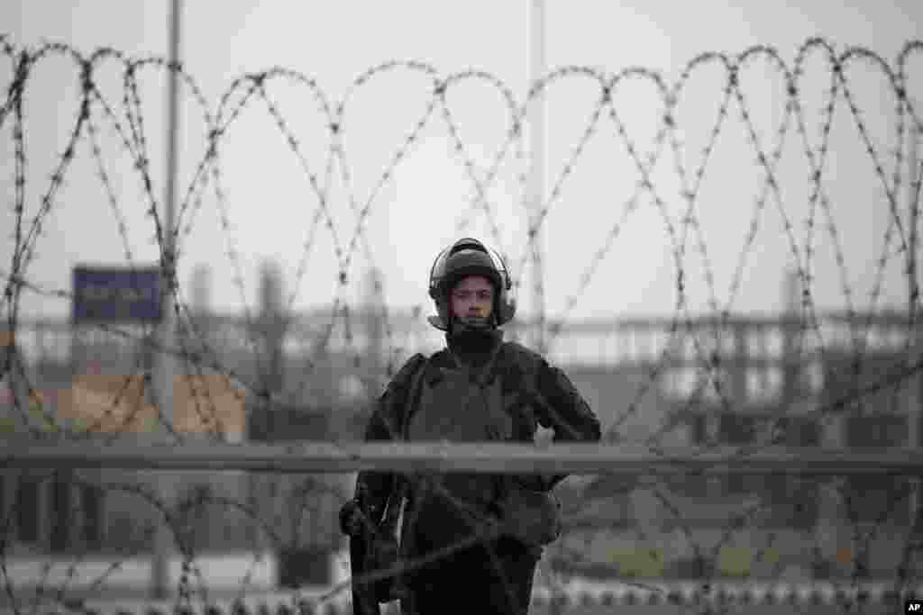 A riot policeman stands guard behind barbed wire outside of a police academy compound where the trial of ousted President Mohammed Morsi is being held, Cairo, Egypt.