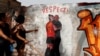 Las mujeres señalan un mural que representa la controversia sobre un beso del jefe de la FA española, Luis Rubiales, a la jugadora Jenni Hermoso durante las celebraciones de la Copa del Mundo, en una pared del Glòries Park en Barcelona, España, el 4 de septiembre de 2023.