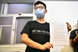 Hong Kong pro-democracy activist Joshua Wong holds up his notice for disqualification at a press conference in Hong Kong on July 31, 2020, a day after he and 11 other activists were barred from standing for election. - The prominent dissident on…