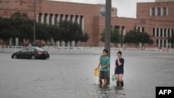 Grant Lu (L) and Naomi Pringle stand in a flooded parking lot on the campus of Rice University afer it was inundated with water from Hurricane Harvey on Aug. 27, 2017 in Houston, Texas.