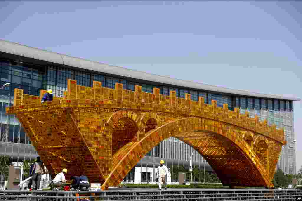 在中国国家会议中心外面的平台上,工人们为大型雕塑《丝路金桥》装置缆线(2017年4月18日)。北京将于国家会议中心举办一带一路峰会。《丝路金桥》桥体全长26米,高6米,宽4米。