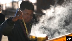 El vapor se eleva en el aire frío mientras un hombre se sirve sopa frente a un refugio para inmigrantes en el vecindario de Pilsen en Chicago, el martes 19 de diciembre de 2023.