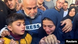 Palestinski novinar Wael Al-Dahdouh grli članove porodice dok prisustvuju sahrani njegovog sina, novinara Hamze Al-Dahdouha, nakon što je ubijen u izraelskom napadu, u Rafahu u južnom pojasu Gaze, 7. januara 2024. godine.