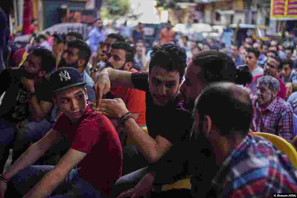 The game is lost, but the exuberance remains. A fan explains to his friends how wrong moves led to Egypt’s defeat.